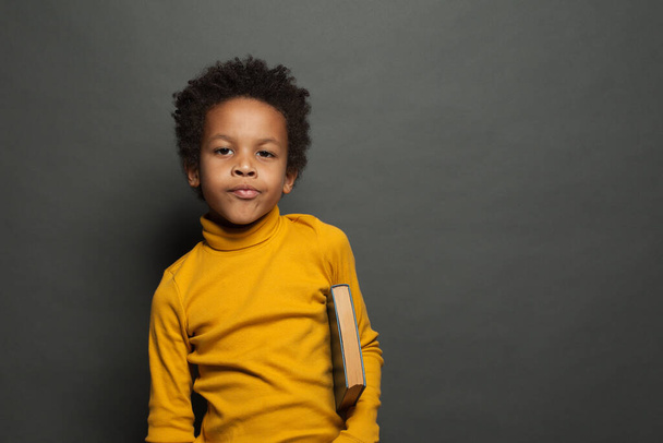 Porträt eines schwarzen Kinderstudenten mit Buch auf Tafelhintergrund - Foto, Bild