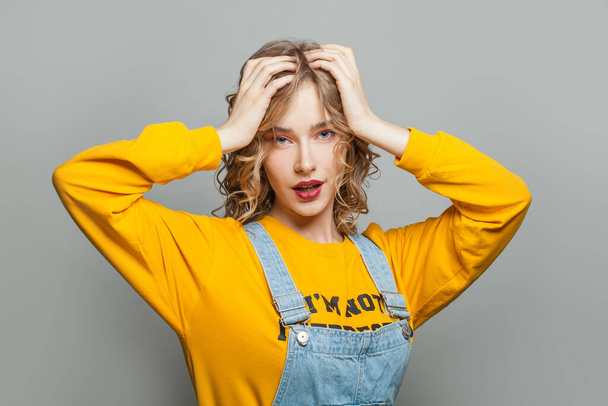 Pretty young woman in yellow sweatshirt on gray background - Foto, afbeelding