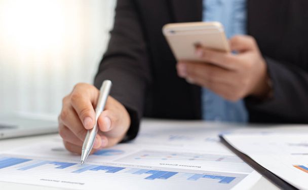 Financiële zakenlieden gebruiken mobiele telefoons om inkomsten te berekenen en gegevens over de financiële prestaties van het bedrijf te analyseren om zich voor te bereiden op de presentatie aan klanten, Fiscaal en boekhoudsysteem concept. - Foto, afbeelding