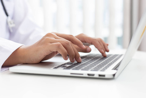 Lekarz używa laptopa do rejestrowania informacji o pacjentach i napisać go na dokumencie, aby przygotować się do diagnozy w pokoju nowoczesnego szpitala, Pomoc w nagłych wypadkach i koncepcji opieki zdrowotnej. - Zdjęcie, obraz