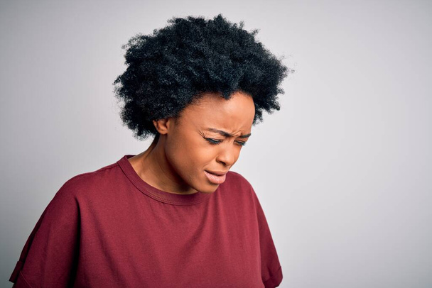 Young beautiful African American afro woman with curly hair wearing casual t-shirt standing with hand on stomach because indigestion, painful illness feeling unwell. Ache concept. - Valokuva, kuva