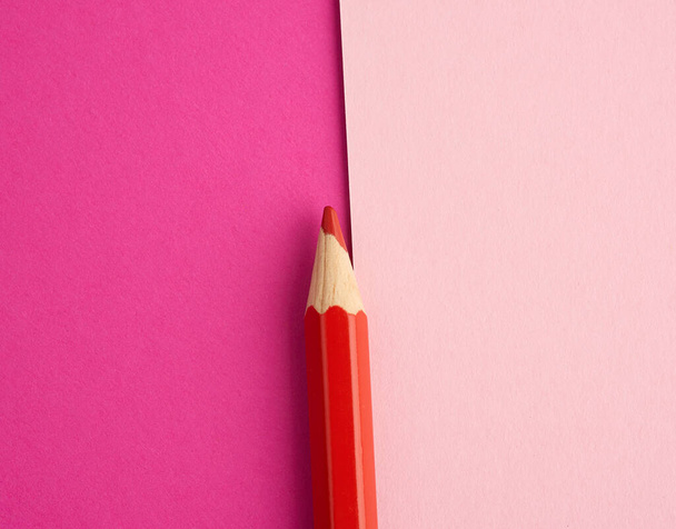 red wooden pencil on a colored background, top view, object for drawing - Fotó, kép
