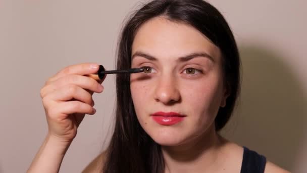 Girl paints eyelashes with black mascara. Daily makeup. - Кадры, видео