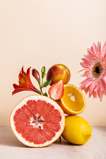 floral and fruit composition with gerbera, Alstroemeria, citrus fruits, strawberry and peach on beige background - Photo, Image