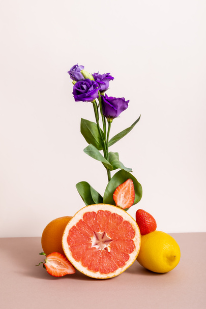 composição floral e frutífera com eustoma roxo e frutos de verão isolados em bege
 - Foto, Imagem