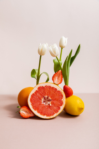 floral and fruit composition with tulips and summer fruits isolated on beige - Foto, imagen