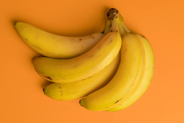 Bunch of ripe bananas on a bright background. Spotted overripe tropical fruits. View from above. Abstract diet concept - Photo, Image