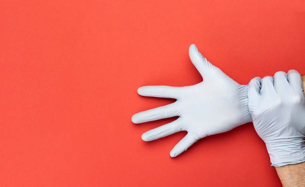 Infectie preventie Medische handschoenen - Virus bescherming apparatuur op rode achtergrond. Corona Virus pandemische bescherming door het wassen van de handen vaak. Professionele veiligheid en hygiëne - Foto, afbeelding