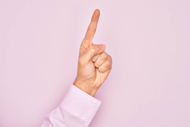Χέρι του Καυκάσου νεαρός άνδρας δείχνει τα δάχτυλα πάνω από απομονωμένο ροζ φόντο καταμέτρηση νούμερο ένα χρησιμοποιώντας δείκτη δάχτυλο, δείχνει την ιδέα και την κατανόηση - Φωτογραφία, εικόνα