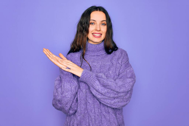 Young beautiful woman wearing casual turtleneck sweater standing over purple background clapping and applauding happy and joyful, smiling proud hands together - Photo, Image
