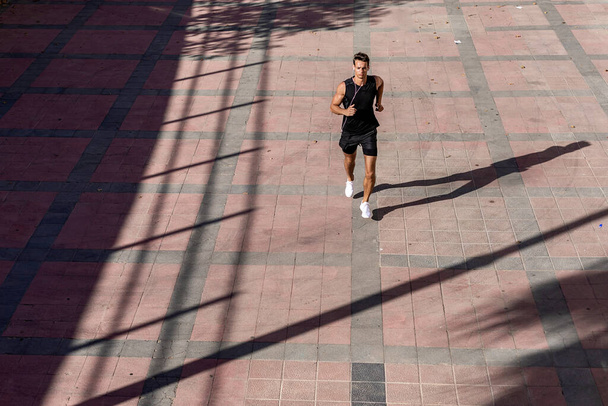 Above view athlete runner training at road in black sportswear. - Foto, Bild