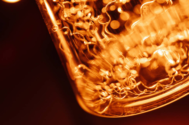 Abstract macro photo of lightbulb. Detail of a decorative lightbulb close-up with shallow depth of field. orange tinting - Φωτογραφία, εικόνα