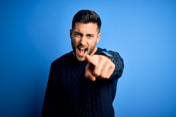 Young handsome man wearing casual sweater standing over isolated blue background pointing displeased and frustrated to the camera, angry and furious with you - Photo, Image
