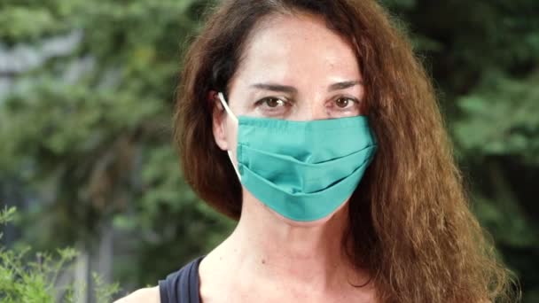 Retrato de uma mulher usando uma máscara protetora no verão olhando câmera, ao ar livre
 - Filmagem, Vídeo