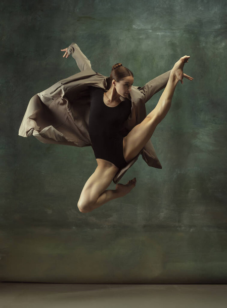 Young graceful tender ballerina on dark studio background - 写真・画像