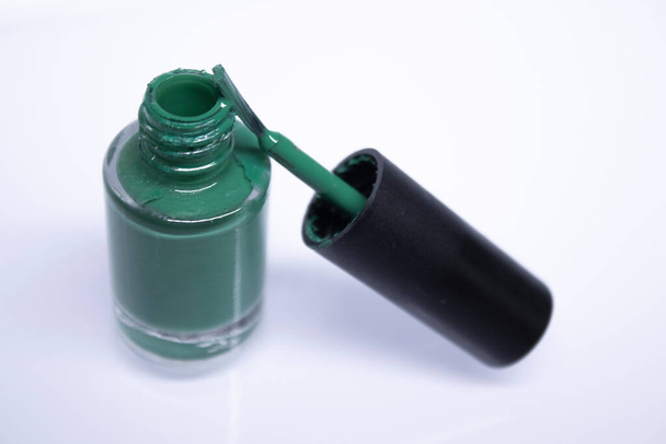 Eine Flasche mit verschüttetem grünen Nagellack auf weißem Hintergrund. Nagellack. Nail Maniküre Konzept. Isolierter Kopierraum - Foto, Bild