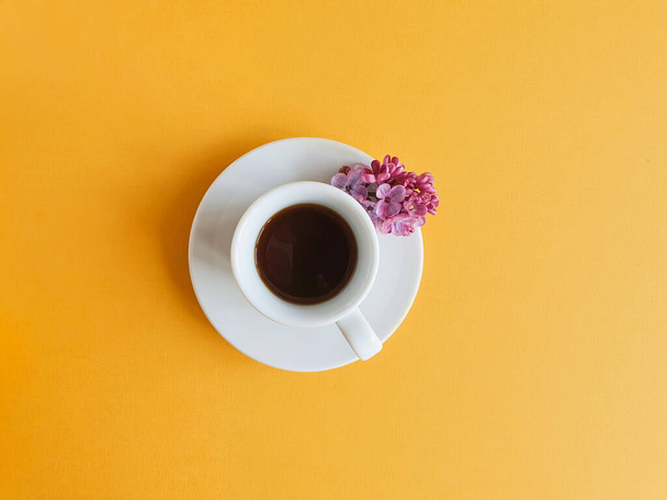 White cup with black coffee on a bright yellow background. View from above. Good morning and the beginning of a new day concept. - Foto, afbeelding