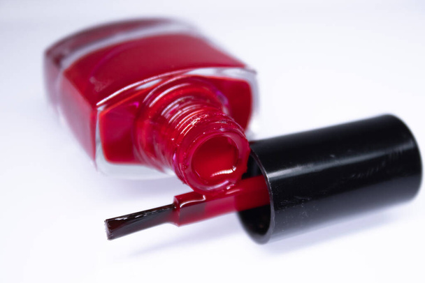 Una botella con esmalte rojo derramado sobre fondo blanco. laca de uñas. Concepto de manicura de uñas. Espacio aislado, copia
 - Foto, imagen