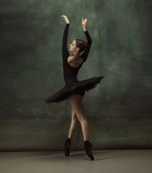 Young graceful tender ballerina on dark studio background - Foto, Imagen