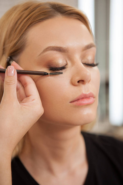 Vertikale Aufnahme einer professionellen Kosmetikerin beim Auftragen von Wimpernverlängerungen auf eine Kundin - Foto, Bild