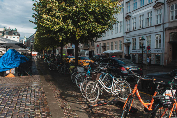 COPENHAGEN, DENMARK - APRIL 30, 2020: Bicycles near road on urban street with sunlight  - Фото, изображение