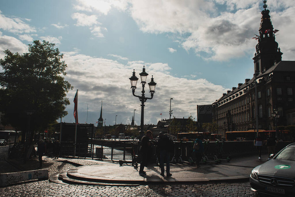 COPENHAGEN, DENMARK - APRIL 30, 2020: People on urban street with Christiansborg Palace and cloudy sky at background  - Φωτογραφία, εικόνα