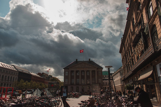 COPENHAGEN, DENMARK - APRIL 30, 2020: Bicycles on city square with buildings and cloudy sky at background  - Foto, imagen