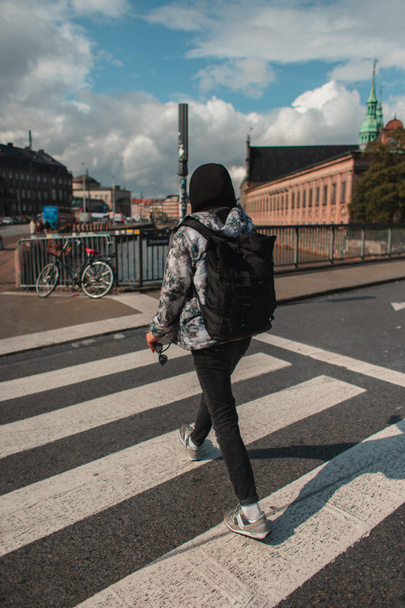 Widok z tyłu człowieka spacerującego po skrzyżowaniu na słonecznej ulicy w Kopenhadze, Dania  - Zdjęcie, obraz