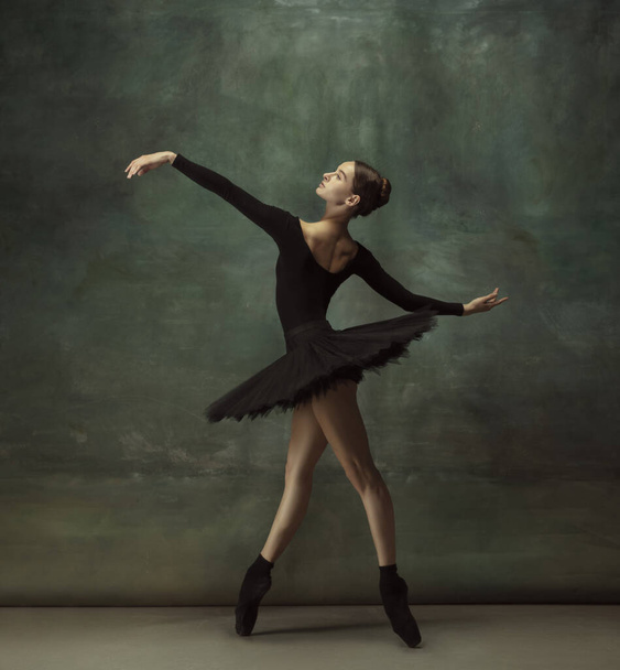 Young graceful tender ballerina on dark studio background - Foto, Imagen
