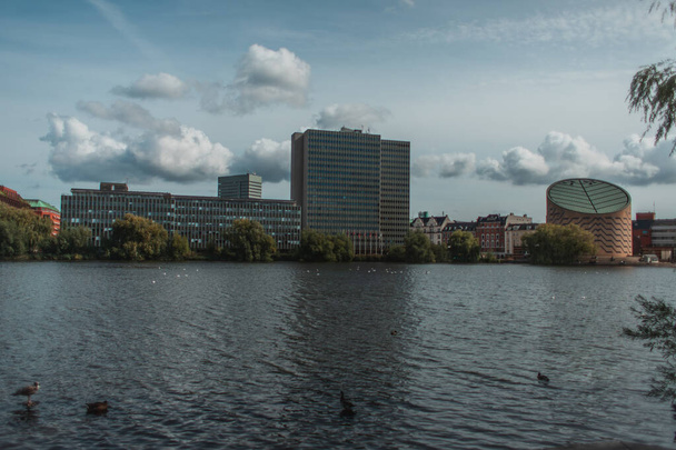 Selektiver Fokus der Enten auf den Fluss mit Gebäuden und bewölktem Himmel im Hintergrund, Kopenhagen, Dänemark  - Foto, Bild