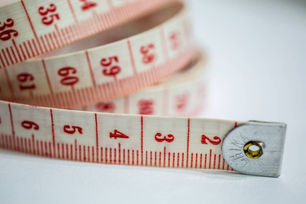 A closeup shot of a white and red tape measure on the table under the lights - designing concept - Valokuva, kuva