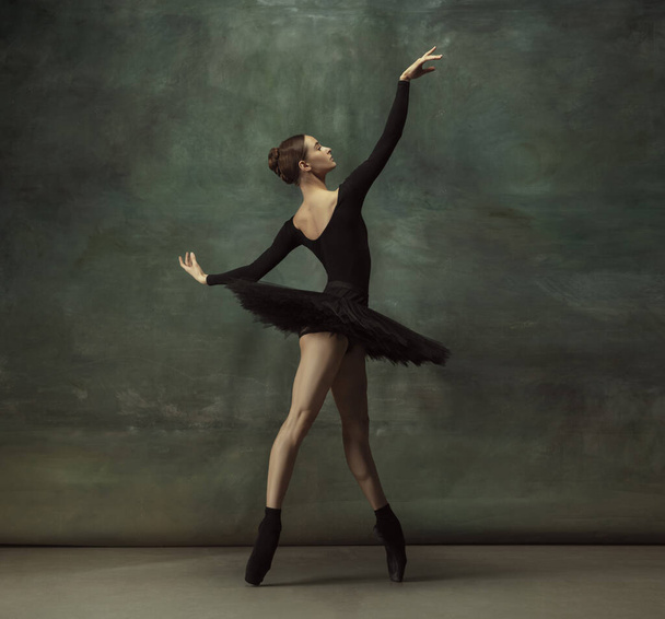 Young graceful tender ballerina on dark studio background - Fotó, kép