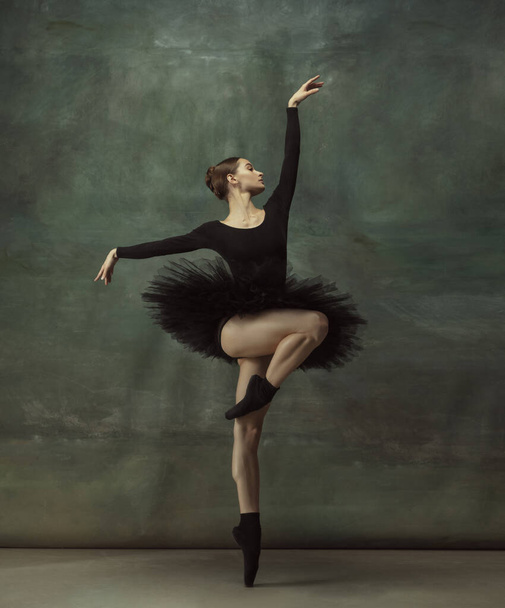 Jonge sierlijke tedere ballerina op donkere studio achtergrond - Foto, afbeelding