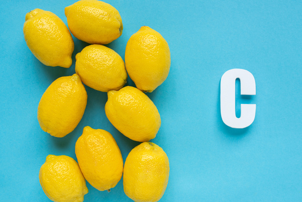 vista superior de limones amarillos maduros y letra C sobre fondo azul
 - Foto, imagen