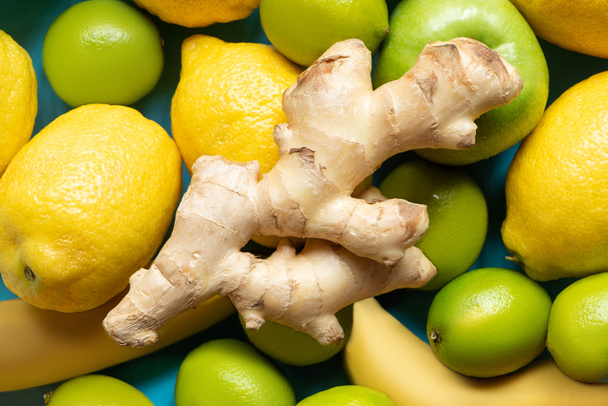 top view of ginger root on yellow lemons, bananas, green apples and limes - Foto, imagen