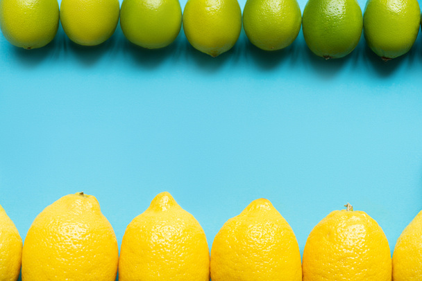 top view of ripe yellow lemons and limes on blue background with copy space - Foto, afbeelding