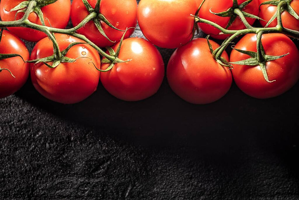 A closeup shot of fresh cherry tomatoes on a black background - 写真・画像