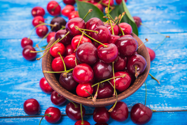 czerwone świeże owoce wiśni na niebieskim drewnianym stole. słodki deser spożywczy. - Zdjęcie, obraz