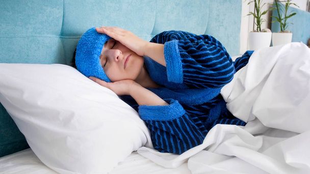 Portrait de jeune femme avec mal de tête couché au lit avec compresse froide sur la tête
 - Photo, image