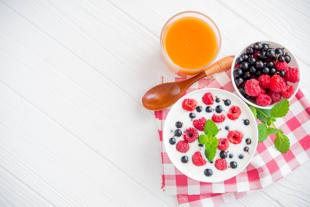 sweet food yoghurt with raspberry fruit and fresh mint , glass of juice, on white wooden background - Fotó, kép