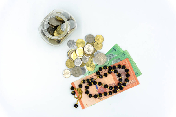 Coins, bank notes and rosary over white background - Photo, Image