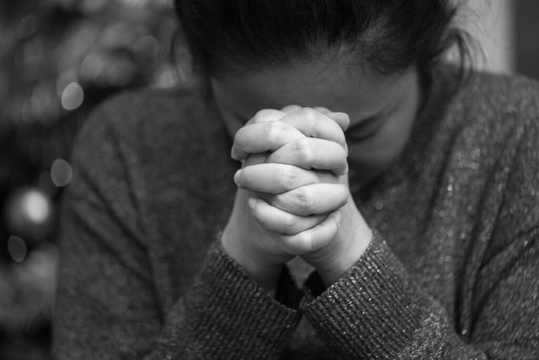A koncepció fekete-fehér képe. Egy ázsiai nő kapaszkodik Istenbe azzal, amit gyógyítani szeretne. Szomorúság, fájdalom, remény és szeretet a bokeh háttérben. - Fotó, kép