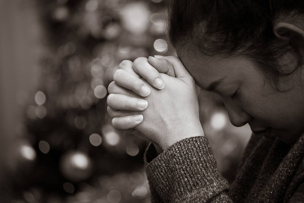 Ein Schwarz-Weiß-Bild des Konzepts. Eine Asiatin klammert sich mit Heilungswünschen an Gott. Traurigkeit, Schmerz, Hoffnung und Liebe im Bokeh-Hintergrund. - Foto, Bild