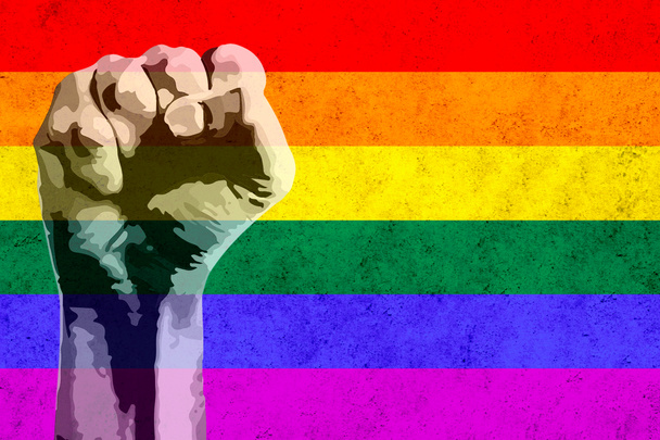 Концепция гордости. Поднятый кулак просит свободы и равенства с флагом lgbt в фоновом режиме и с копировальным пространством
. - Фото, изображение