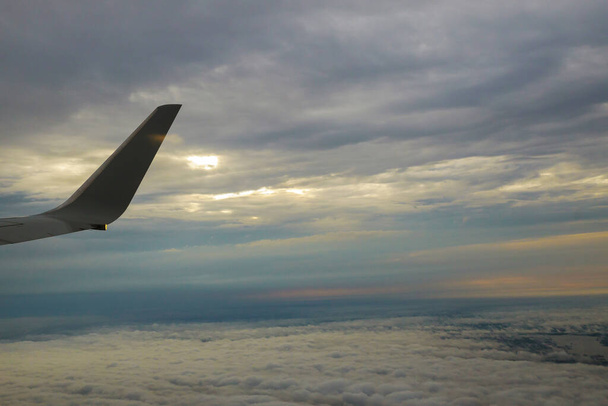Tragfläche eines Flugzeugs, das während des Fluges über den Morgenwolken fliegt. - Foto, Bild