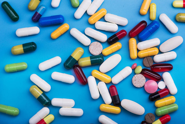 Colored pills and medical capsule on blue background - Fotoğraf, Görsel