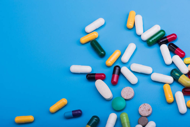 Colored pills and medical capsule on blue background - Foto, Imagem