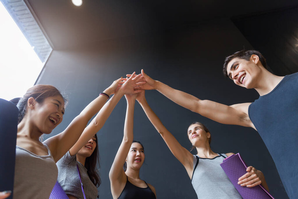 Group of various young sporty people standing against the wall. Students taking a rest from fitness activity, waiting for a lesson to start, close up. Healthy lifestyle concept - Photo, image
