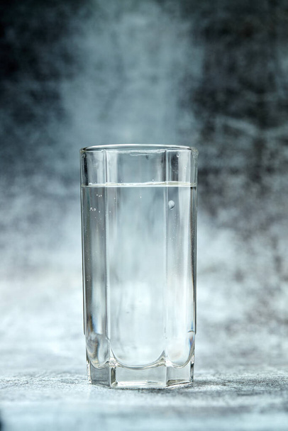 灰色の背景に輝く水のガラス、近景 - 写真・画像