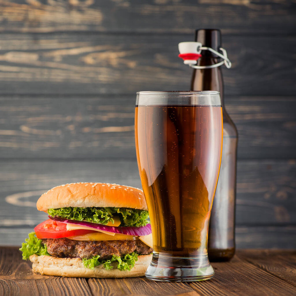 Grand burger savoureux et verre à bière sur table en bois
 - Photo, image